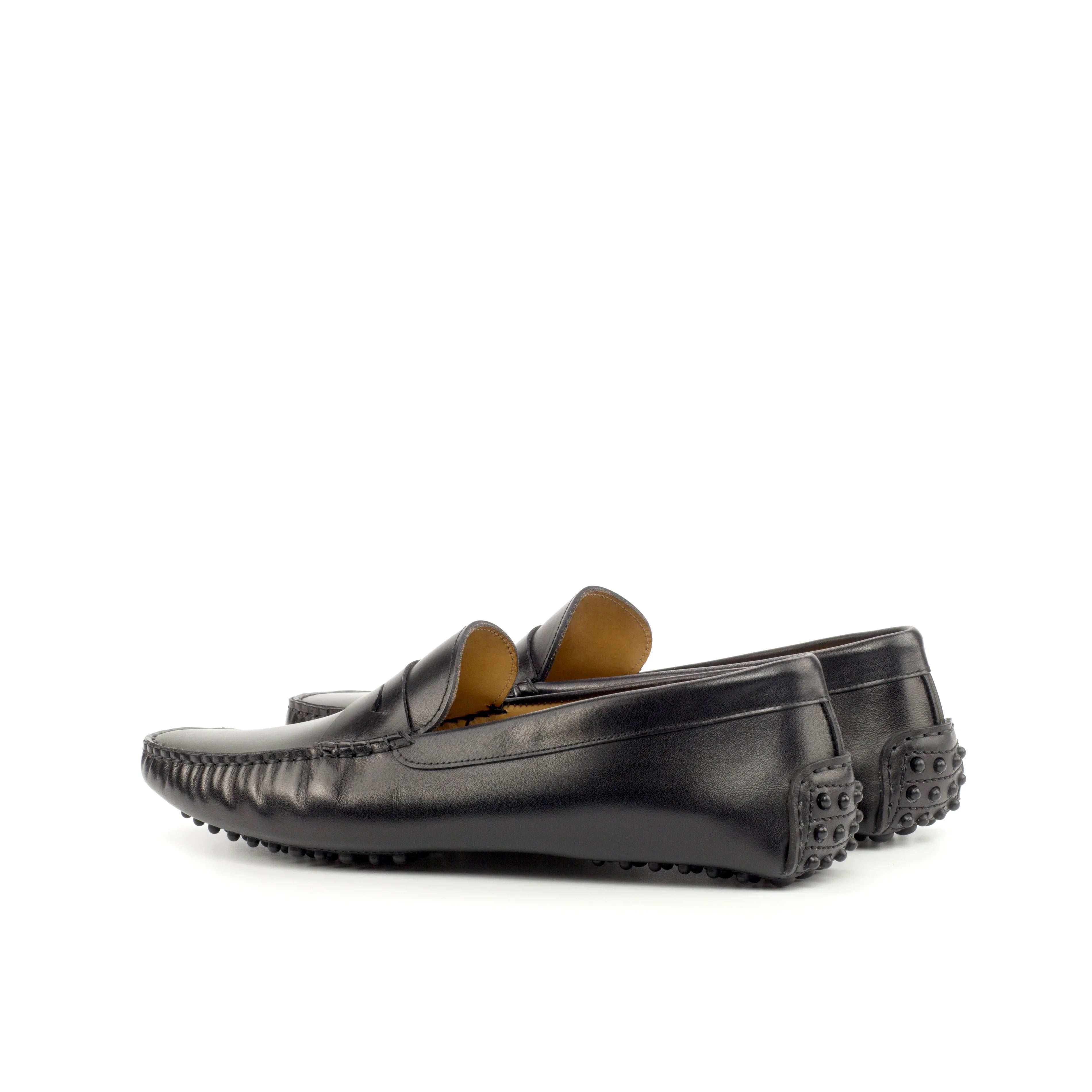 Side view of black nappa leather penny driving loafers with detailed stitching along the vamp and a distinctive penny keeper strap, presented on a white backdrop.