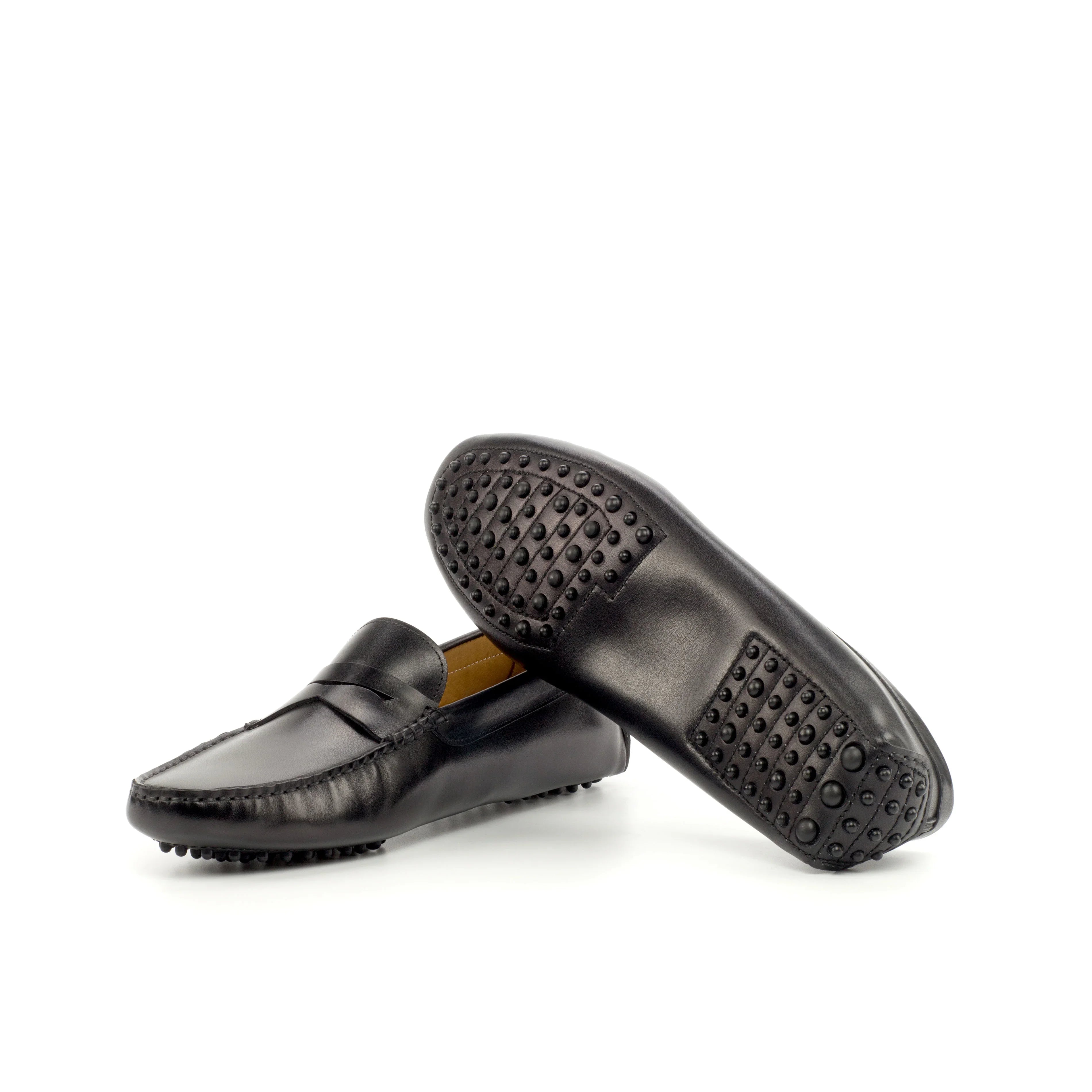 An image displaying the unique pebbled sole of a black nappa leather penny driving loafer, highlighting the rubber nubs for grip and comfort.