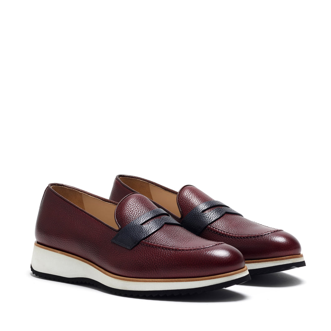 Elegant front view of burgundy calf leather penny loafers featuring a contrasting navy band, set on a contemporary white and black chunky sole.