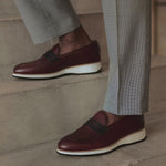 Stylish shot of a person wearing the burgundy penny loafers, perfectly paired with grey trousers, exemplifying sophistication.