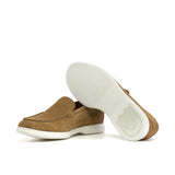 Underside view of a camel suede casual loafer, highlighting the patterned white sole designed for grip and durability, presented on a white surface.