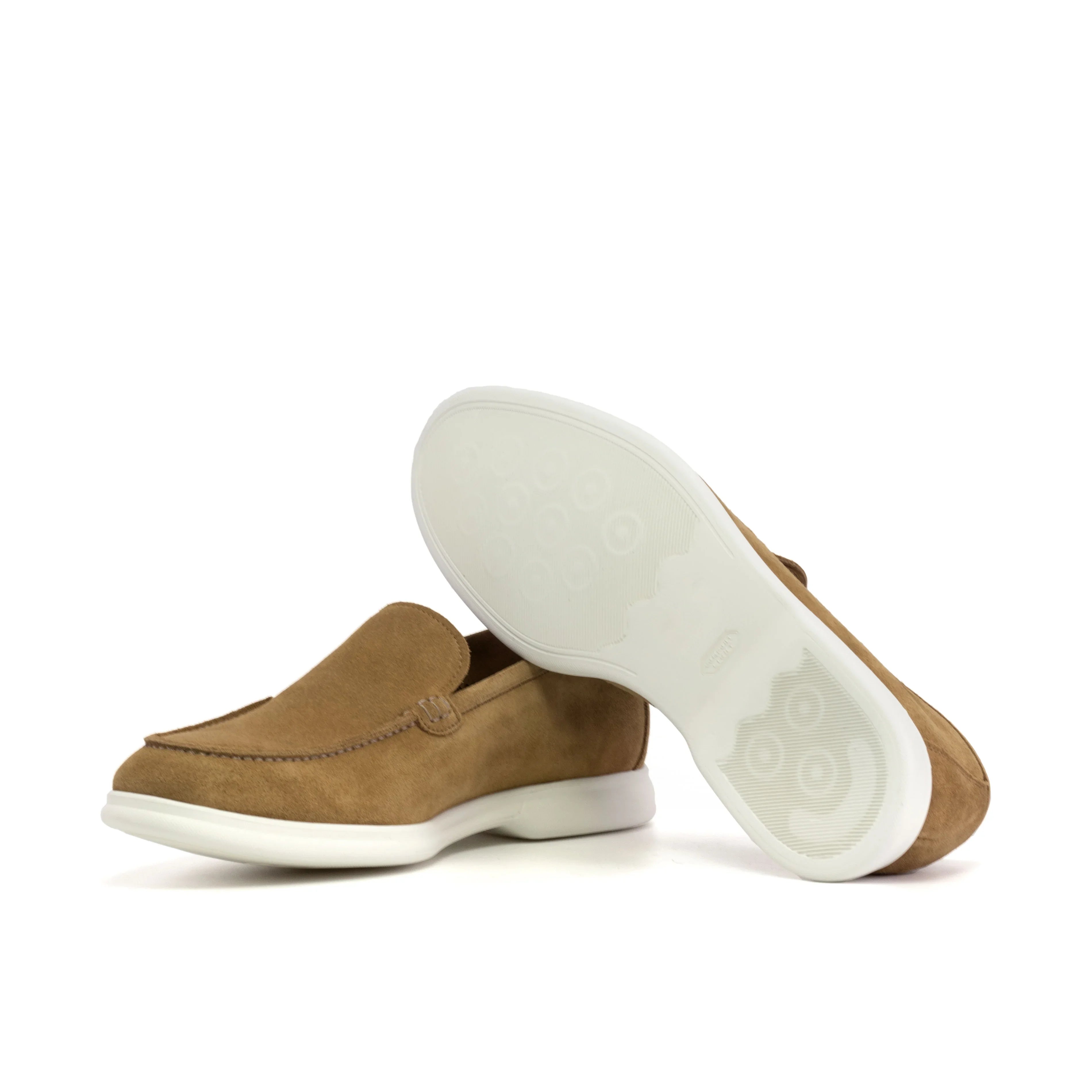 Underside view of a camel suede casual loafer, highlighting the patterned white sole designed for grip and durability, presented on a white surface.