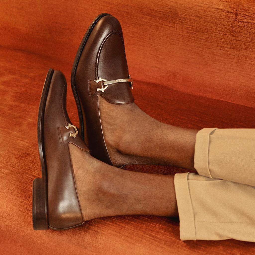 Lifestyle image featuring a person wearing dark brown calf leather horsebit loafers, paired with beige trousers, capturing the footwear's versatility and classic style.