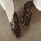 Casual lifestyle photo of a model wearing dark brown croco kiltie loafers, paired with light trousers, capturing the shoes' versatility and style.