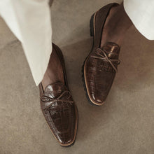 Load image into Gallery viewer, Casual lifestyle photo of a model wearing dark brown croco kiltie loafers, paired with light trousers, capturing the shoes&#39; versatility and style.
