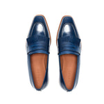 Overhead view of navy blue penny loafers with fringe, revealing the meticulous stitching and the classic penny slot on a white surface.
