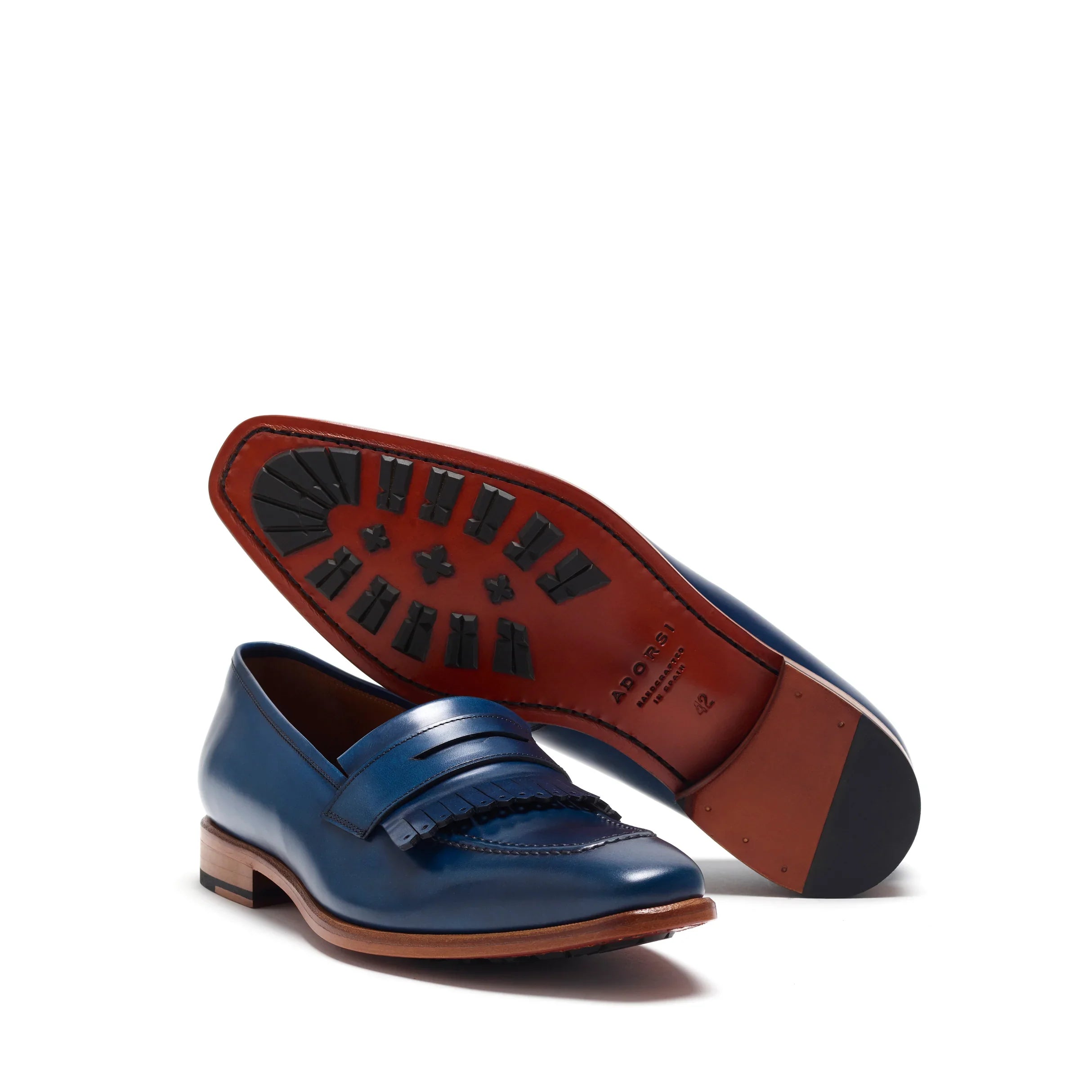 Angled view of the navy loafers highlighting the contrast of the tan leather insole and the textured black rubber studs outsole for grip.