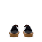 Back view of glossy patent black belgian loafers highlighting the sturdy heel construction with a tan sole, contrast stitching, and a polished finish.