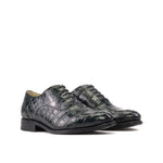 Pair of green crocodile-patterned leather shoes on a white background