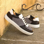 A pair of Black & White Houndstooth Low-Top Sneakers by ADORSI leaning against a wall.